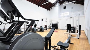 Et fitnesscenter med løbebånd, styrketræningsudstyr og trægulv.