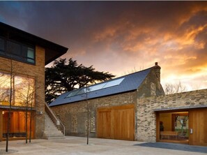 A modern building with a stone facade, large wooden doors, and a staircase leading to an upper level. - Downing College Cambridge (Cambridge)