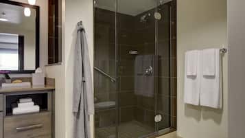 Un baño moderno con ducha de vidrio, inodoro y tocador con espejo y toallero.