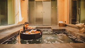 Un área de spa con una bañera de hidromasaje, una pared decorativa y una estatua.