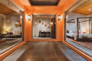 A hotel lobby with a tiled floor, a reception desk, and a glass elevator. - Brij Bageecha Jaipur - Private Villas with Heated Plunge Pool (Jamwa Ramgarh)
