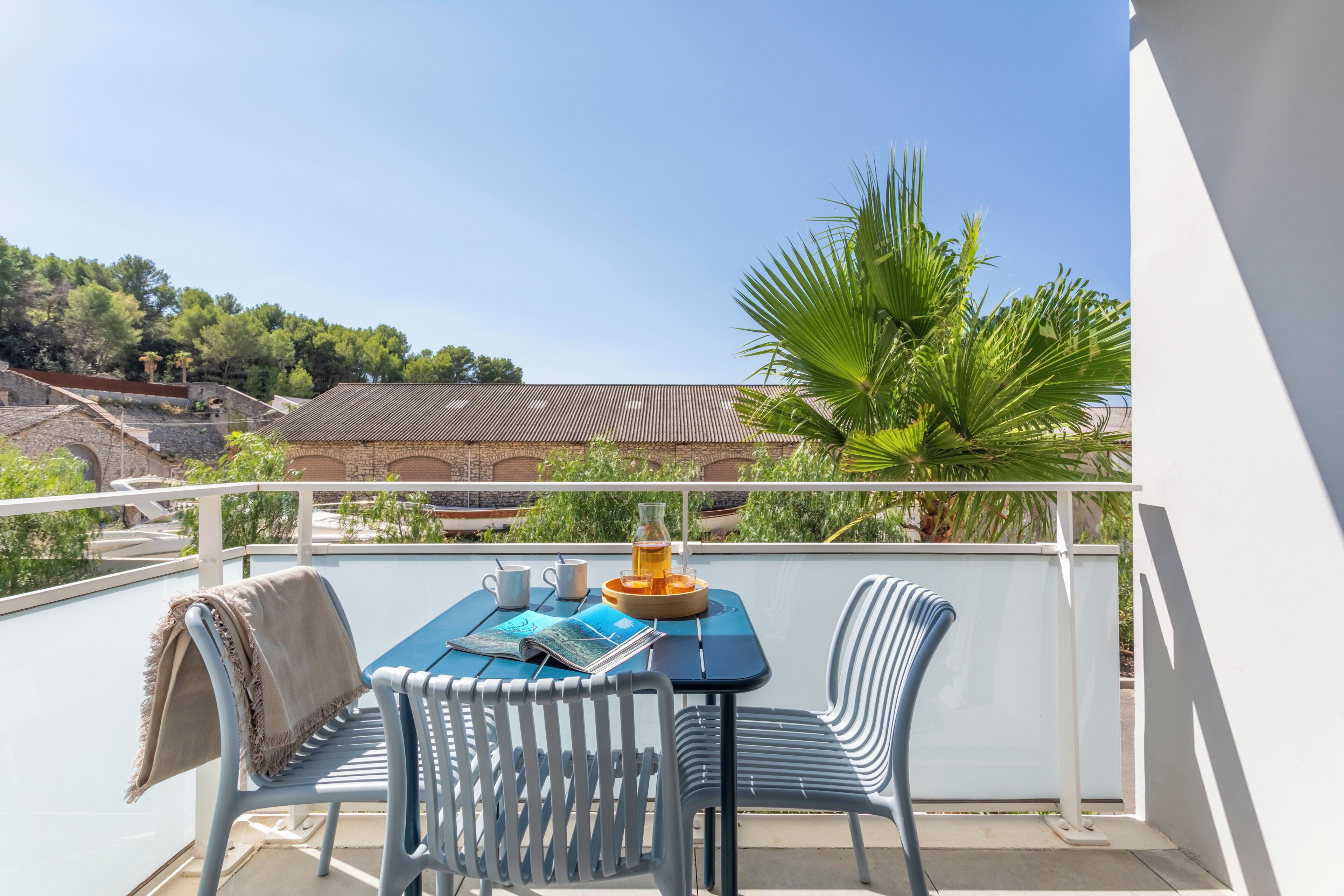 A balcony with a table, chairs, and a magazine.