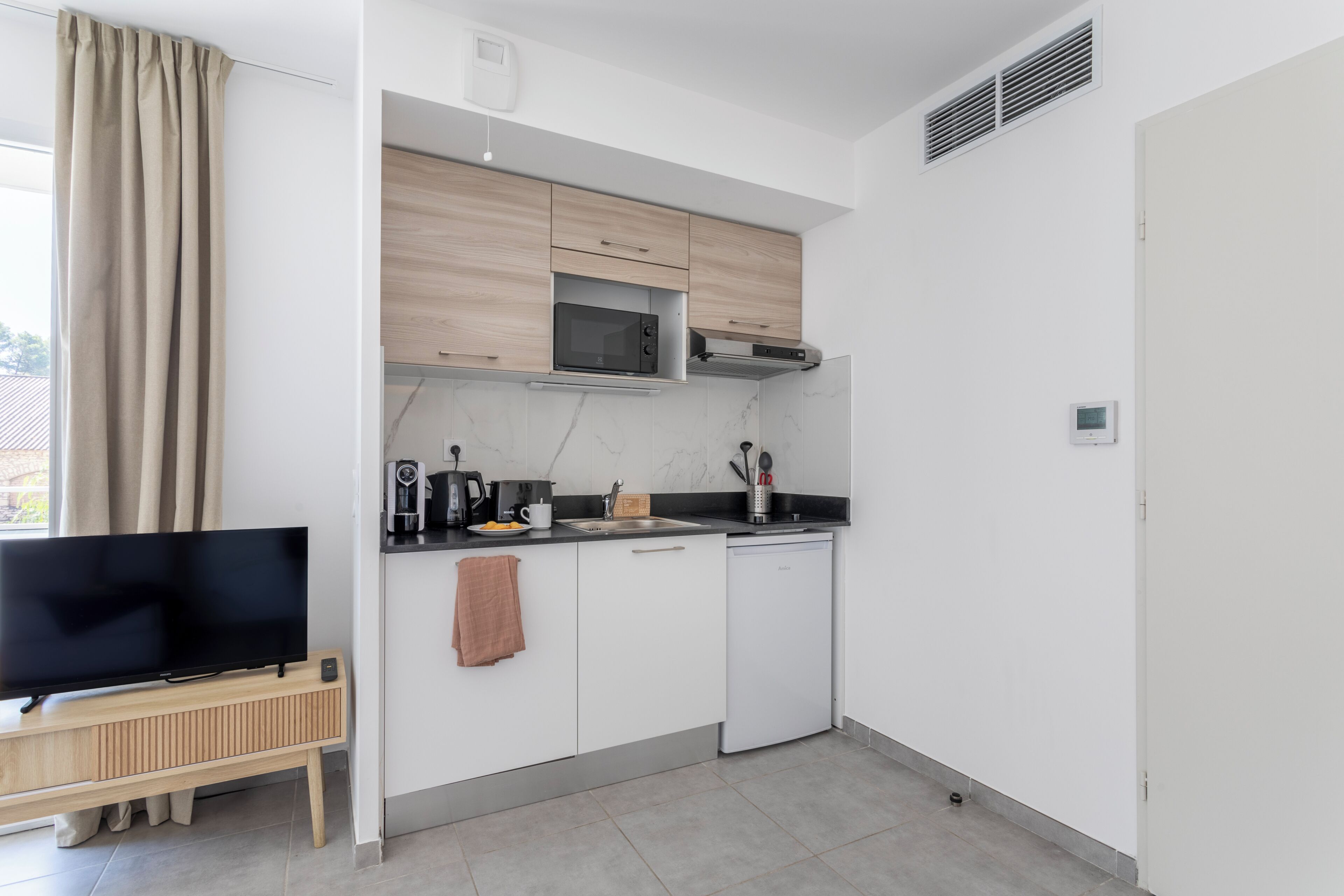 A modern kitchen with a flat-screen TV, microwave, and dishwasher.