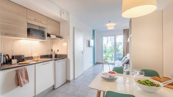 A modern kitchen with built-in appliances, a dining area with a table set for two, and a view of the outdoors.