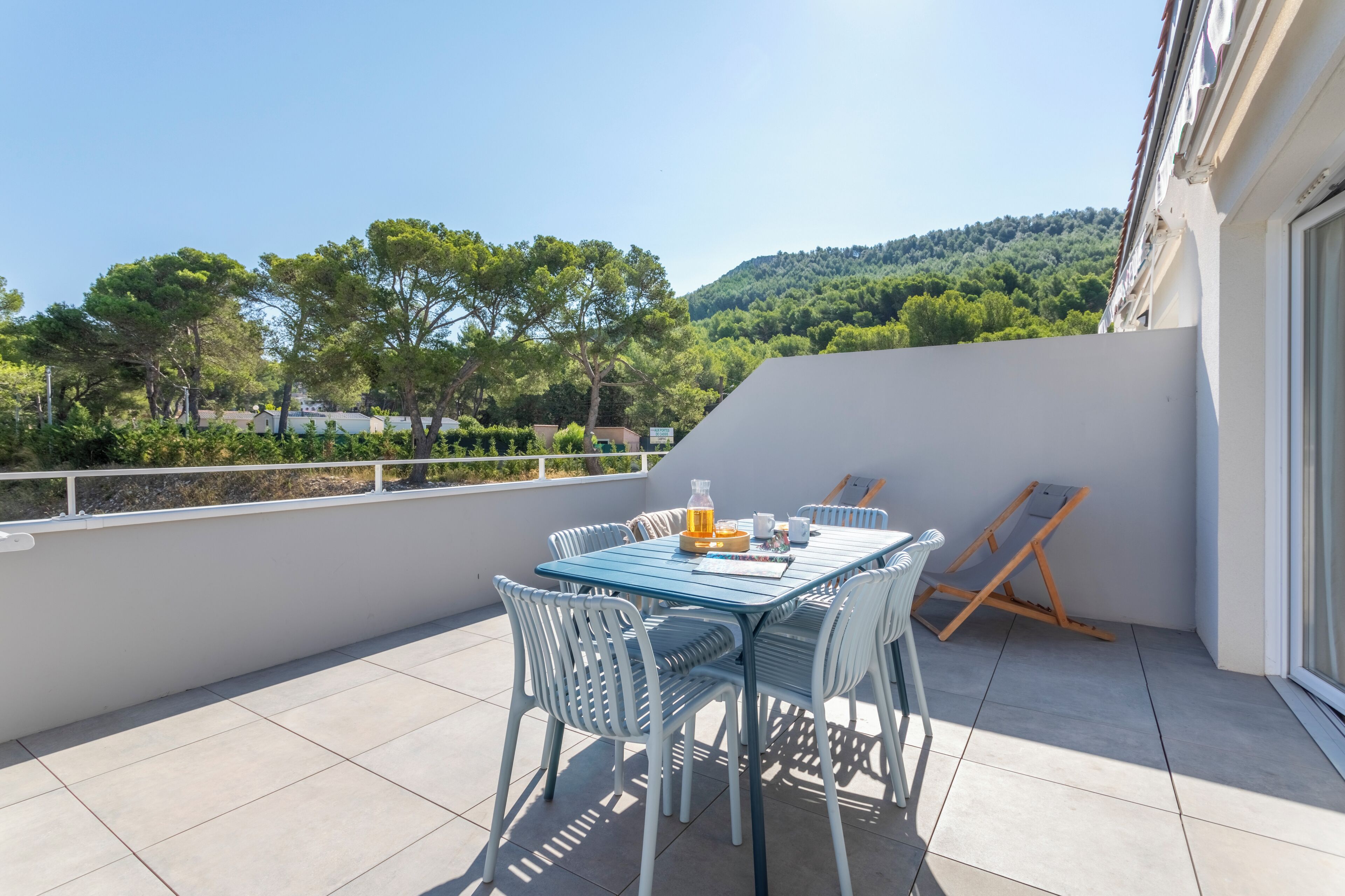 Een balkon met een tafel, stoelen, een fles en een kop.