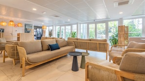 A spacious, well-lit room with a large sofa, wicker chairs, and a small round table. - Résidence Pierre & Vacances Cap Cassis Calanques (Roquefort-la-Bedoule)