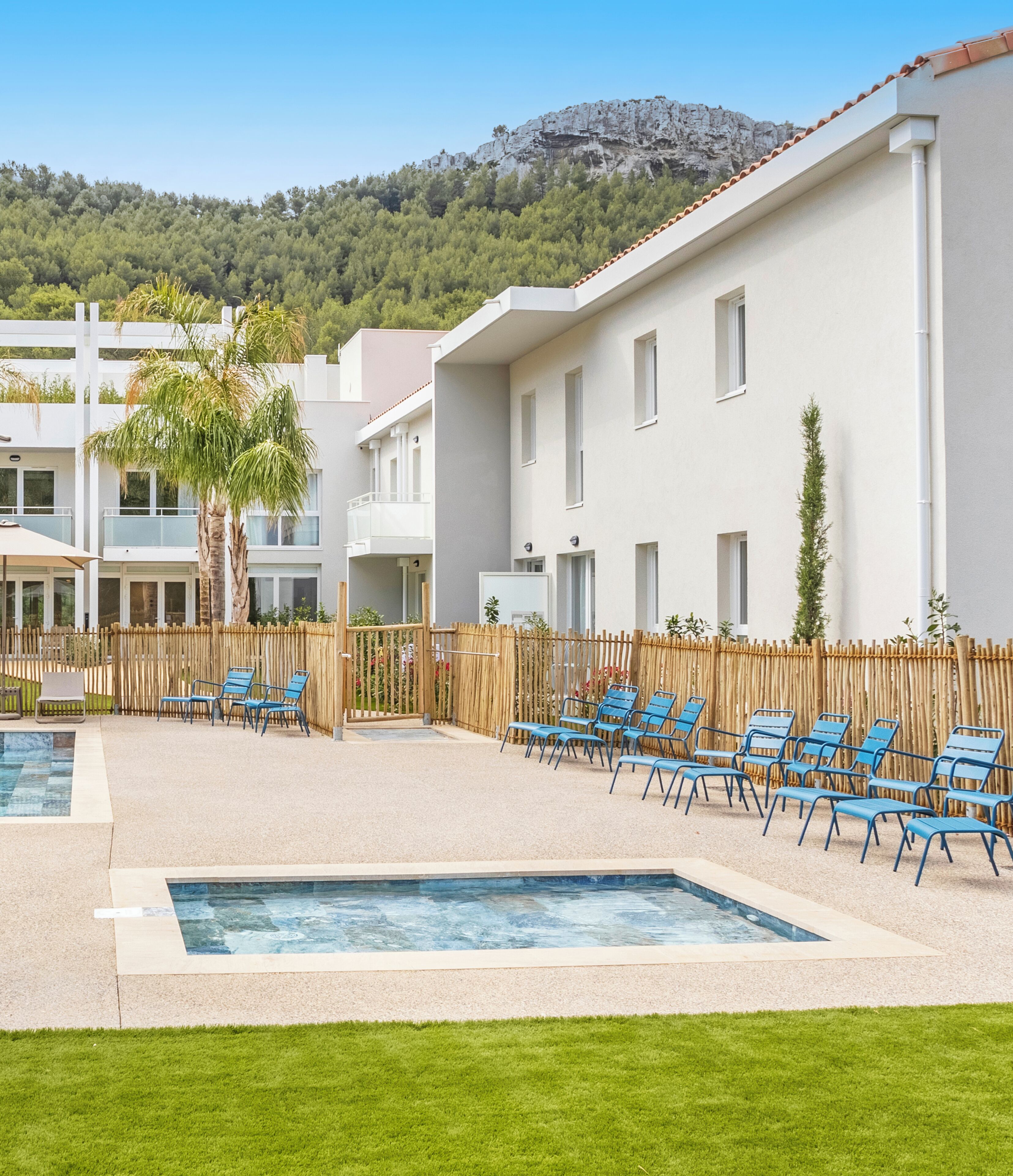 Un complexe hôtelier doté d’une piscine, de chaises longues et offrant une vue sur un paysage montagneux.