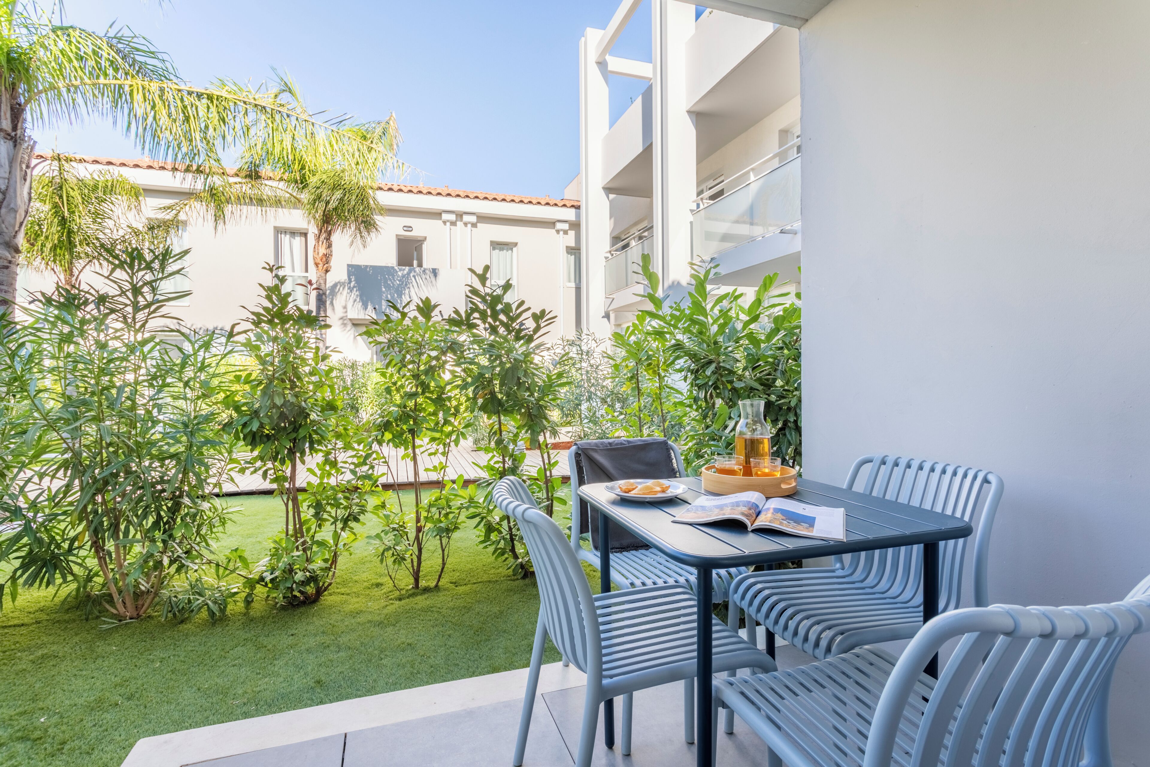 A balcony with a table, chairs, and a potted plant.