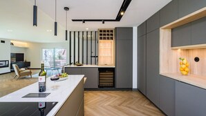 Une cuisine moderne dotée d’un îlot central, d’un réfrigérateur à vin encastré et d’un mur d’accent en bois.