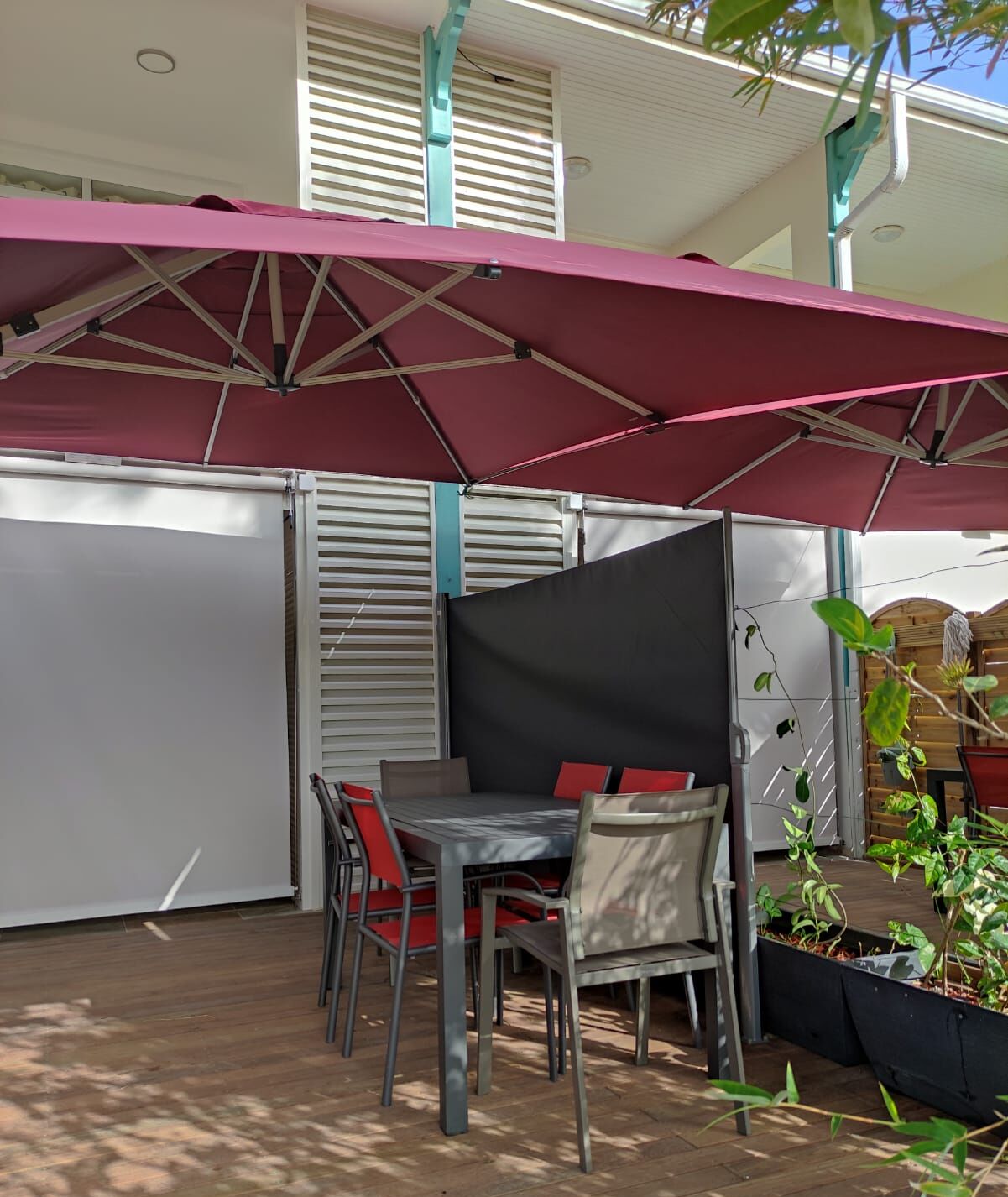 An outdoor patio with a table and chairs, a large umbrella, and a view of the building's exterior.