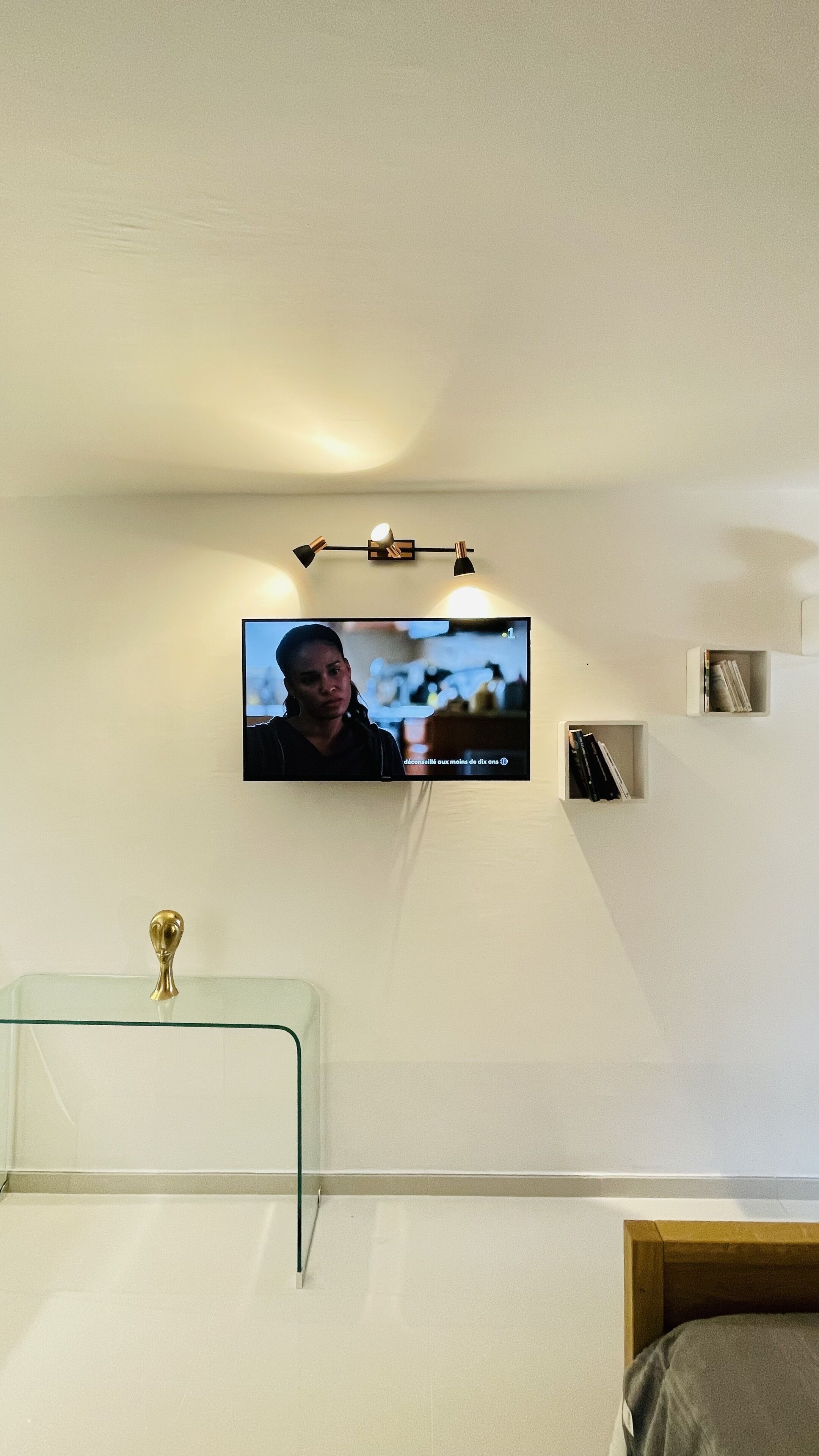 A television mounted on a wall with a shelf below it.