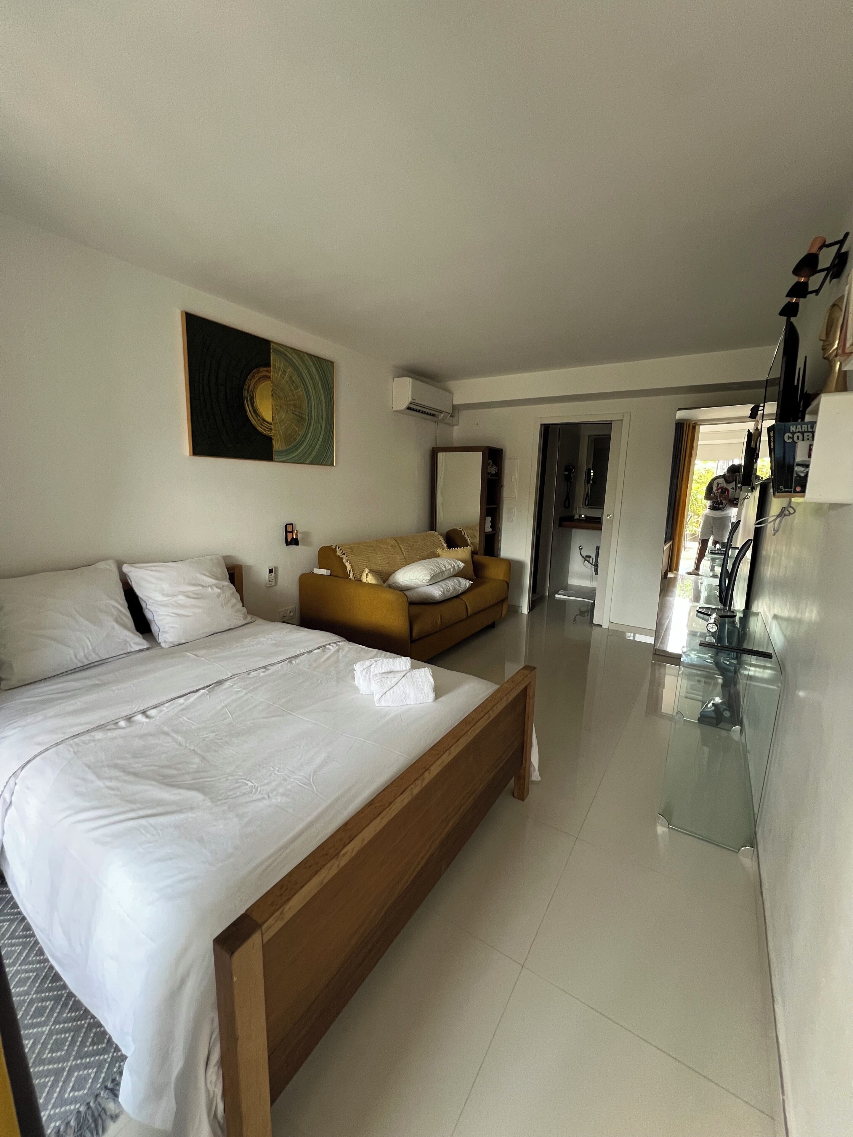 A hotel room with a large bed, a sofa, a dining area, and a kitchen.