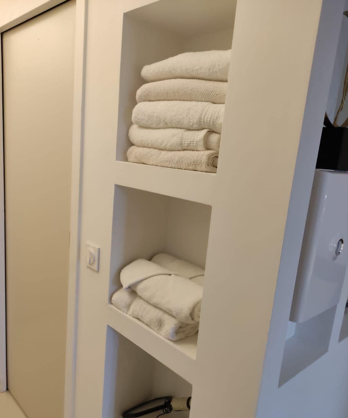 A white closet with multiple shelves holding folded towels.