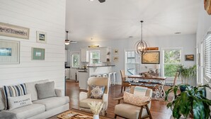 A spacious living room with a sofa, armchairs, and a coffee table. A dining area with a table and chairs is visible in the background. - Good Tides Getaway! (Beaufort)