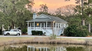 A house with a porch, a driveway, and a pond in front. - Good Tides Getaway! (Beaufort)