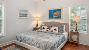 A bedroom with a bed, two nightstands, a ceiling fan, and two windows with blinds. - Good Tides Getaway! (Beaufort)