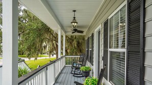 A covered porch with a ceiling fan, rocking chairs, and potted plants. - Good Tides Getaway! (Beaufort)