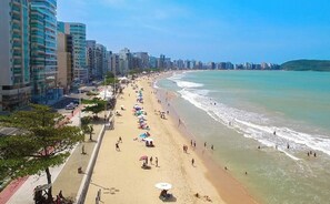 A beach with high-rise buildings, umbrellas, and people. - Beautiful Apartment in Praia do Morro - Renovated - Wi-Fi - Netflix - 300 m from the beach (Guarapari)
