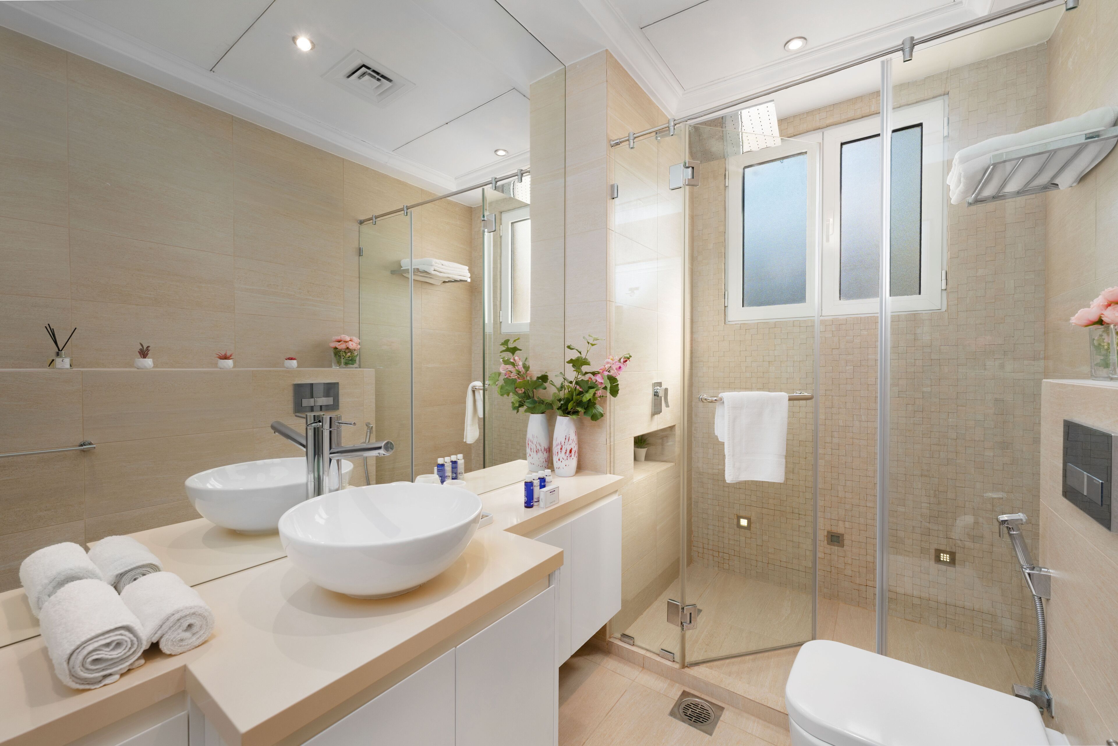 A modern bathroom with a large sink, mirror, and glass shower enclosure.