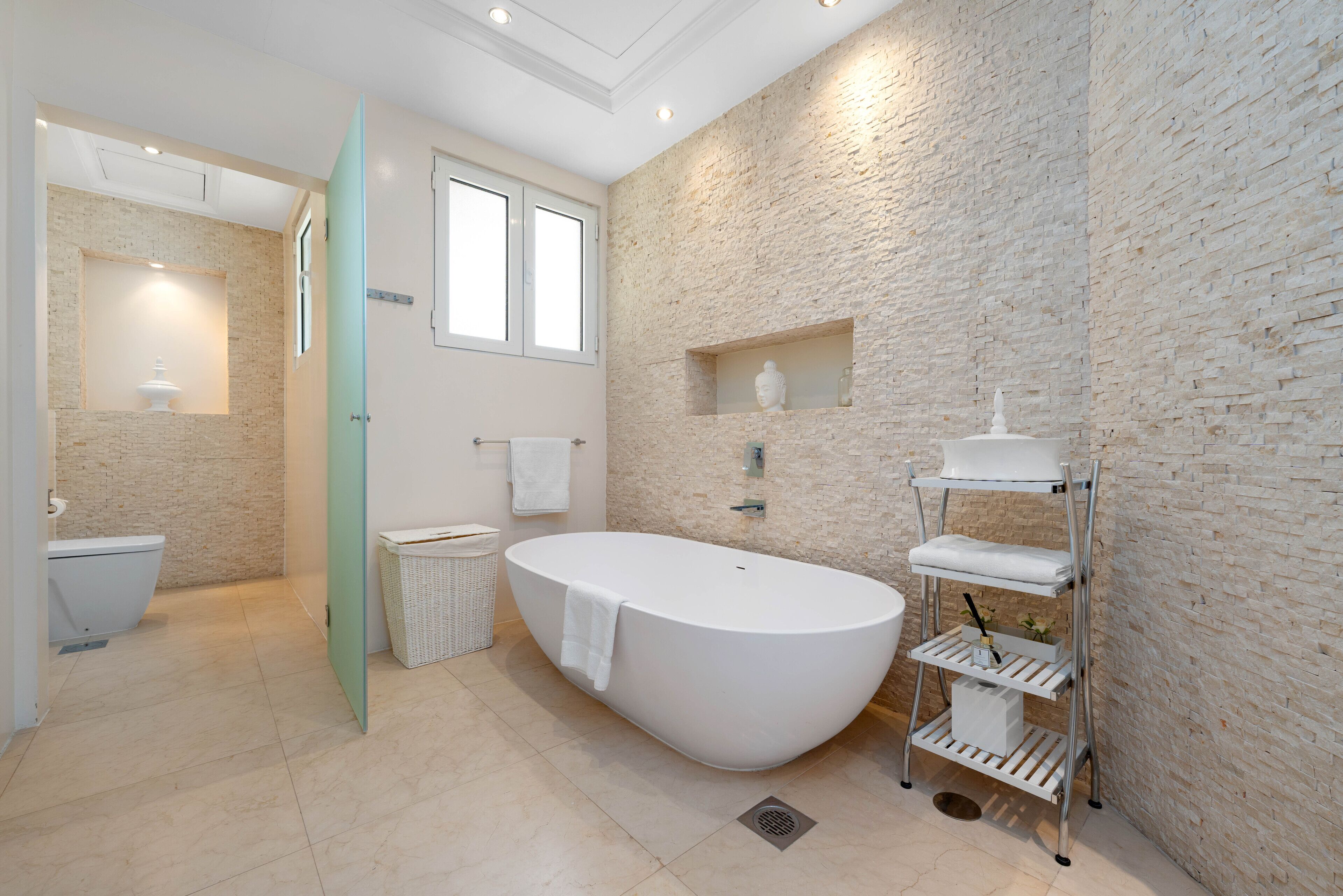 A modern bathroom with a freestanding bathtub, a glass shower enclosure, and a built-in shelf with toiletries.