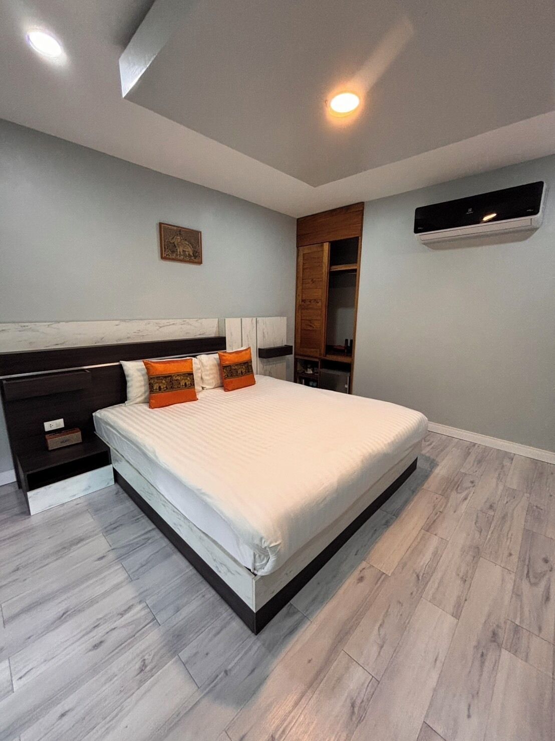 A bedroom with a bed, nightstands, a wardrobe, and a ceiling light.