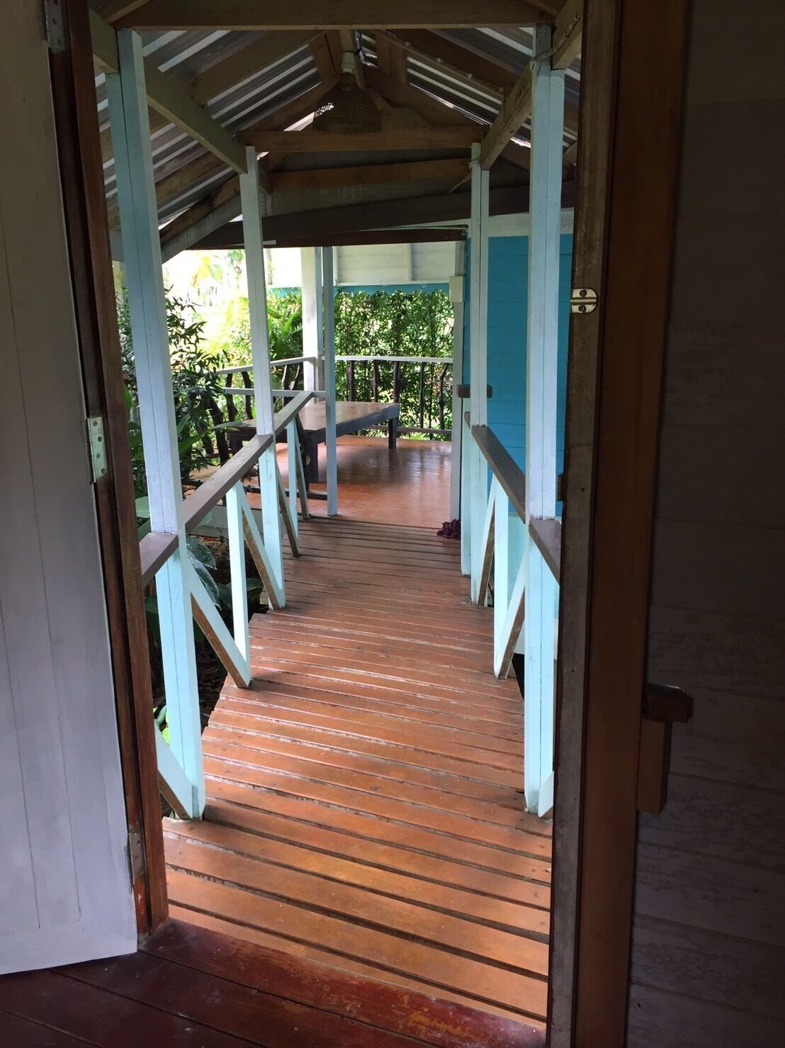 A wooden staircase leading to a covered outdoor area with a metal railing.