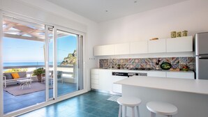 A modern kitchen with a large island, white cabinetry, and colorful backsplash tiles. - Seaview Villa In Mongerbino by Wonderful Italy (Santa Flavia)