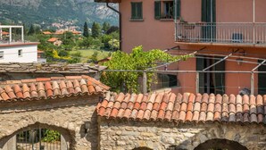 A stone building with a tiled roof, a balcony, and potted plants.