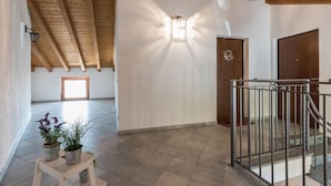 A spacious room with a high ceiling, wooden beams, a light fixture, a door, and a small table with plants.