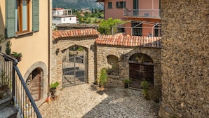 A courtyard with stone archways, a staircase, and buildings with terracotta roofs.