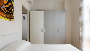 A bedroom with a bed, a wardrobe, and a window with curtains. - Appartamento al Ghetto Ebraico by Wonderful Italy (Bologna)