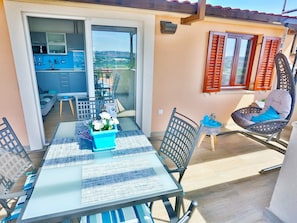 A balcony with a dining table, chairs, a flower vase, and a chair with a cushion. - Apartments Ivan (Solin)
