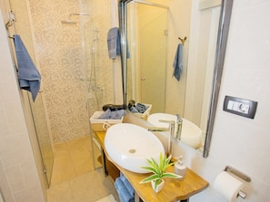 A bathroom with a glass shower enclosure, a sink with a mirror, and a toilet. - Apartments Ivan (Solin)