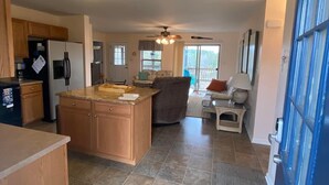 Una cocina amplia con una isla central, armarios de madera y una puerta azul.