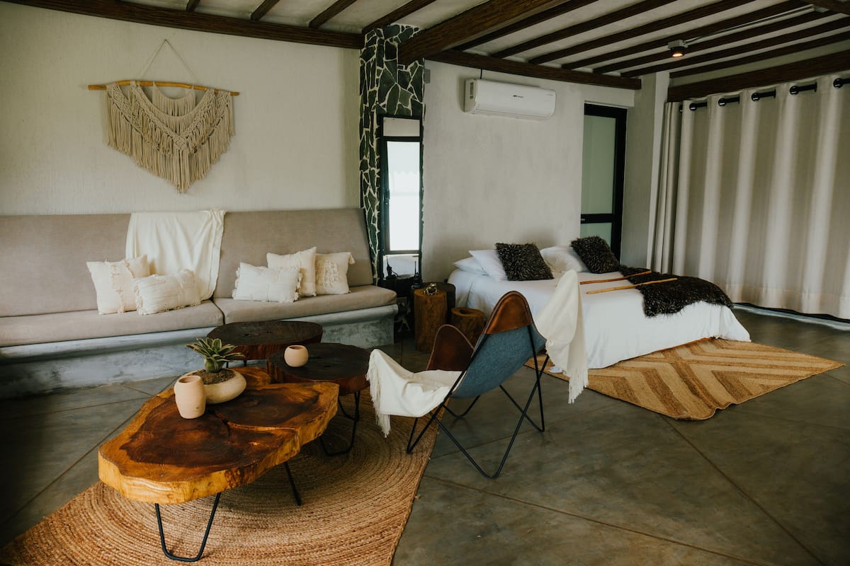 A modern living room with a sofa, a coffee table, and a bed with a patterned bedspread.