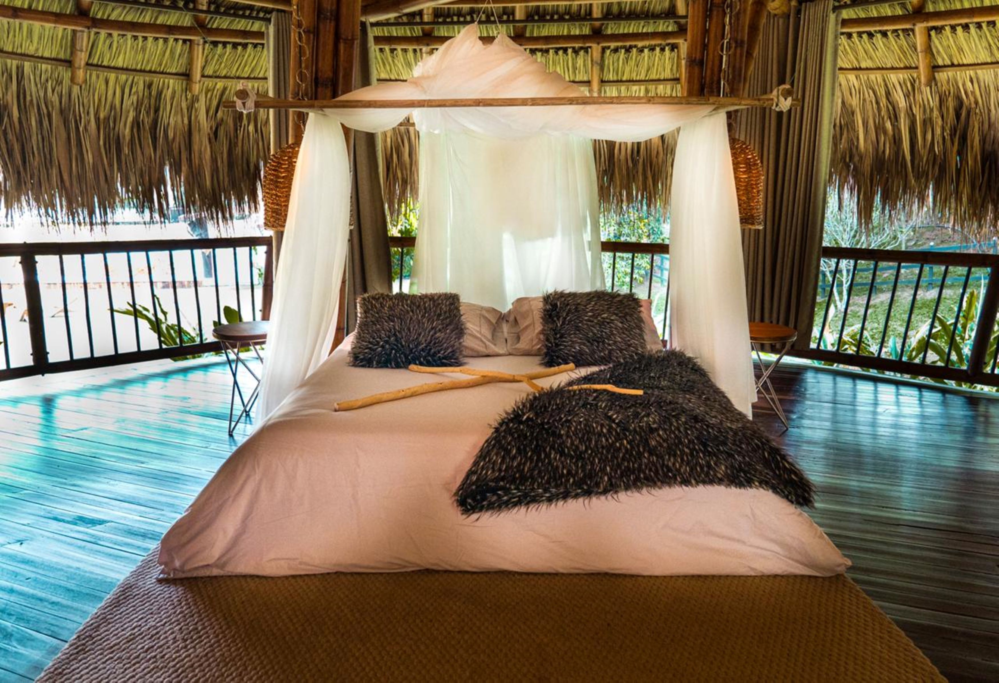 Een bed met een hemelbed, kussens en een houten stok.