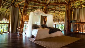 A room with a bed under a canopy, wooden flooring, and a view of greenery outside. - El Río Hotel (Sonson)
