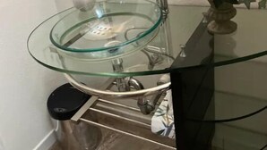 Ein Badezimmer mit einem Waschbecken aus Glas, einem Spiegel und einer Vase mit Blumen.