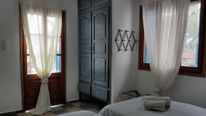 Quarto com duas camas, um guarda-roupa e uma janela com cortinas.