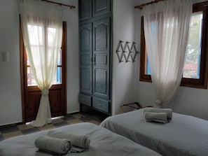 Een kamer met twee bedden, een kledingkast en een raam met gordijnen.
