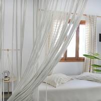 Quarto com cama, janela e cadeira suspensa.