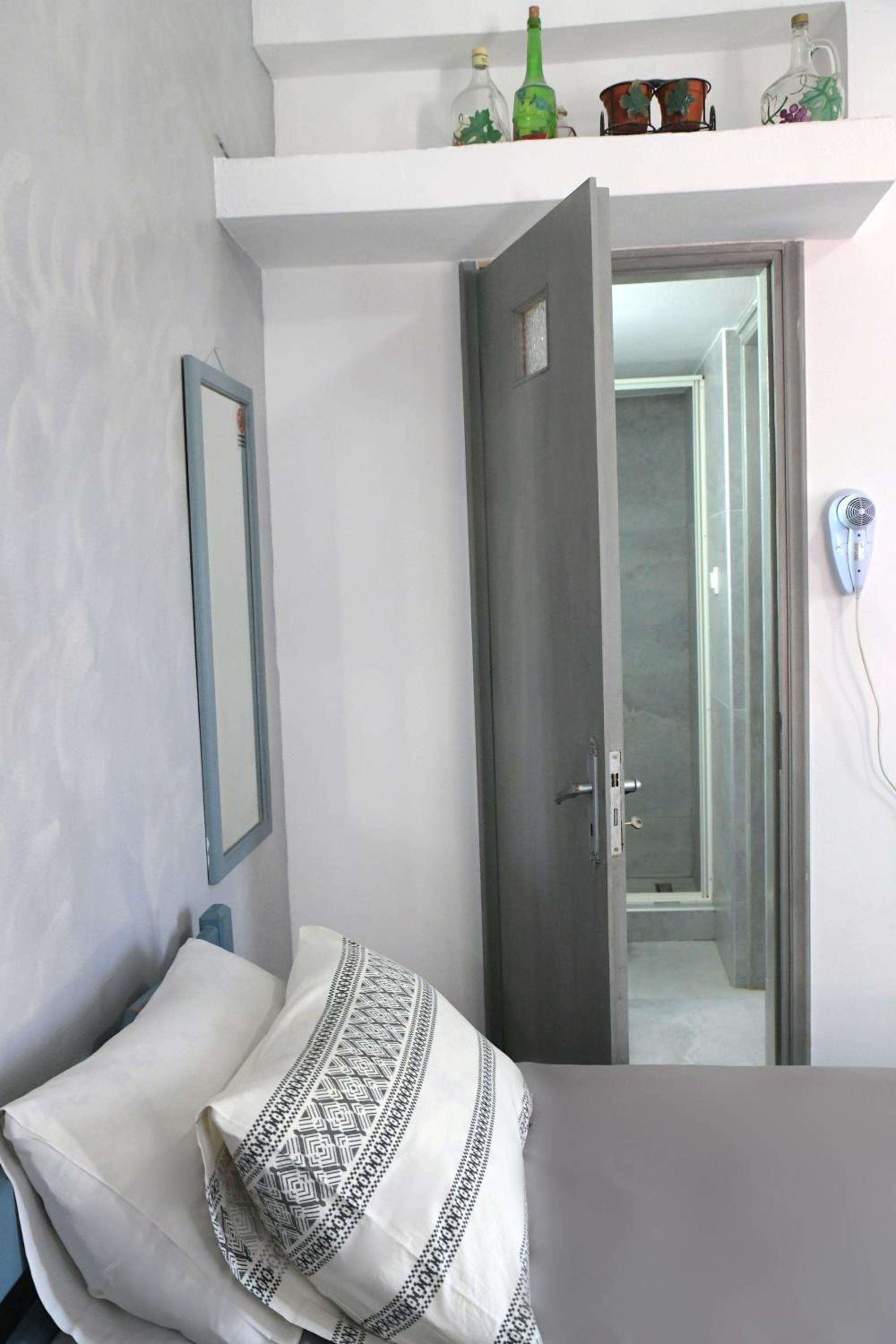 Un dormitorio con cama, armario, espejo y puerta que da a otra habitación.