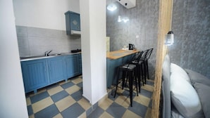 Uma cozinha compacta com armários azuis, piso xadrez e um balcão com banquetas.