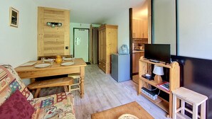 A cozy room with a wooden dining table, a sofa, a television, and a small wooden cabinet.