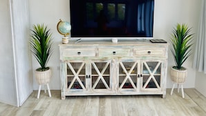 A white cabinet with drawers and glass doors, a globe, and two potted plants.