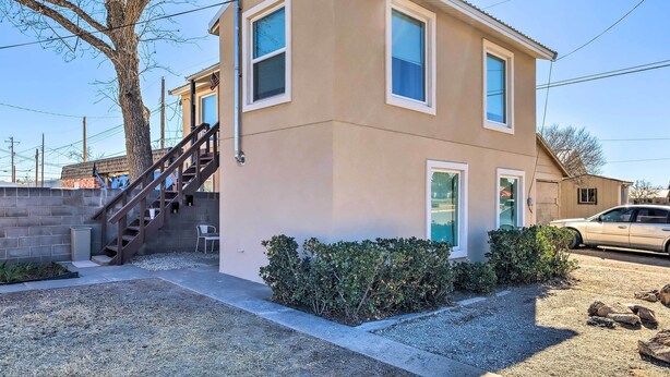 A two-story building with a beige exterior, a staircase leading to the upper floor, and a small front yard with a hedge and gravel path. - Pecos Vacation Rental Near Rodeo Arena! (Pecos)