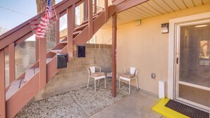 A staircase with a red handrail leading to a door with a glass panel, two white chairs, and an American flag. - Pecos Vacation Rental Near Rodeo Arena! (Pecos)