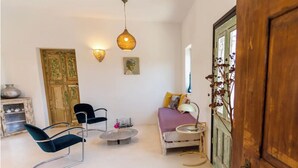 Un salon chaleureux avec un canapé, deux fauteuils, une petite table basse et une lampe décorative.