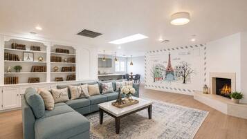 Ein Wohnzimmer mit Ecksofa, Couchtisch, Kamin und einer Wand mit Stadtbild-Wandgemälde.
