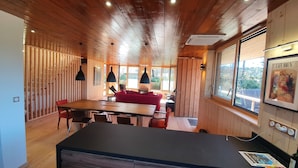 A wooden interior with a dining area, red sofa, and a kitchen counter.